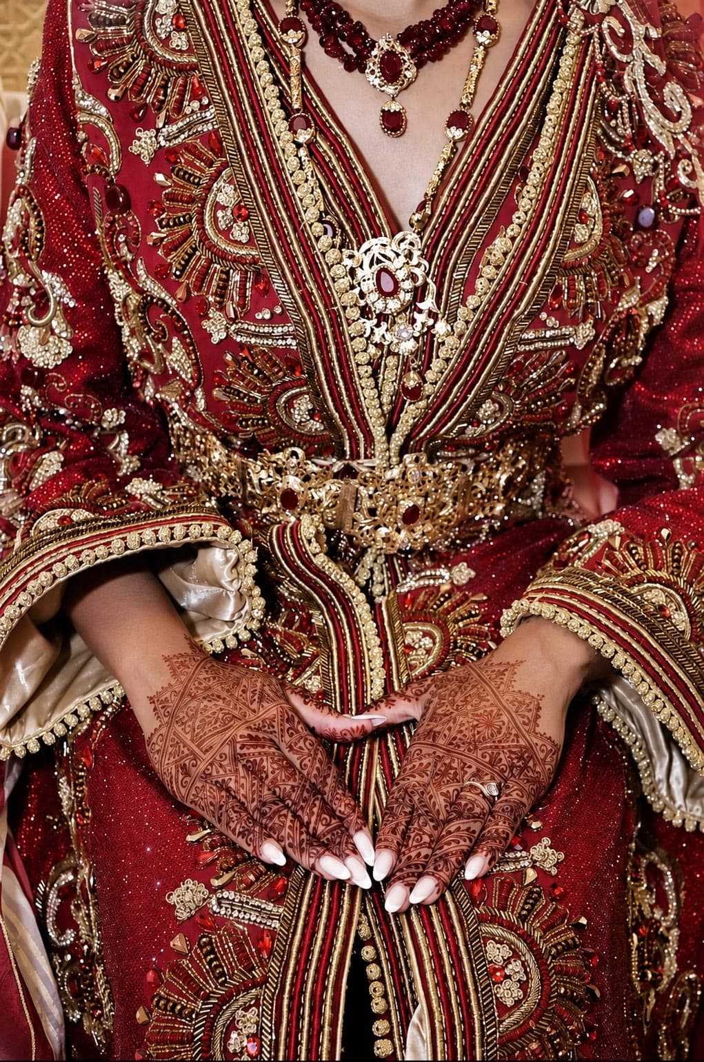 Mariée en caftan bordeaux et or, mains ornées de henné